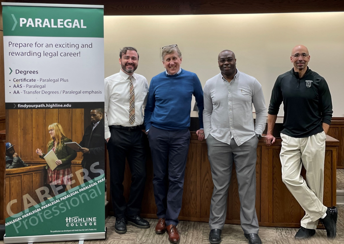 Photo of Professors Joshua Brumley, Bruce Lamb, Kevin Rainge, Che Dawson in the Courtroom highlighting sign for Paralegal Careers at Highline College - Prepare for and exciting and rewarding legal career - Degrees: Certificate-Paralegal Plus, AAS-Paralegal, AA-Transfer Degrees/Paralegal emphasis - findyourpath.highline.edu
